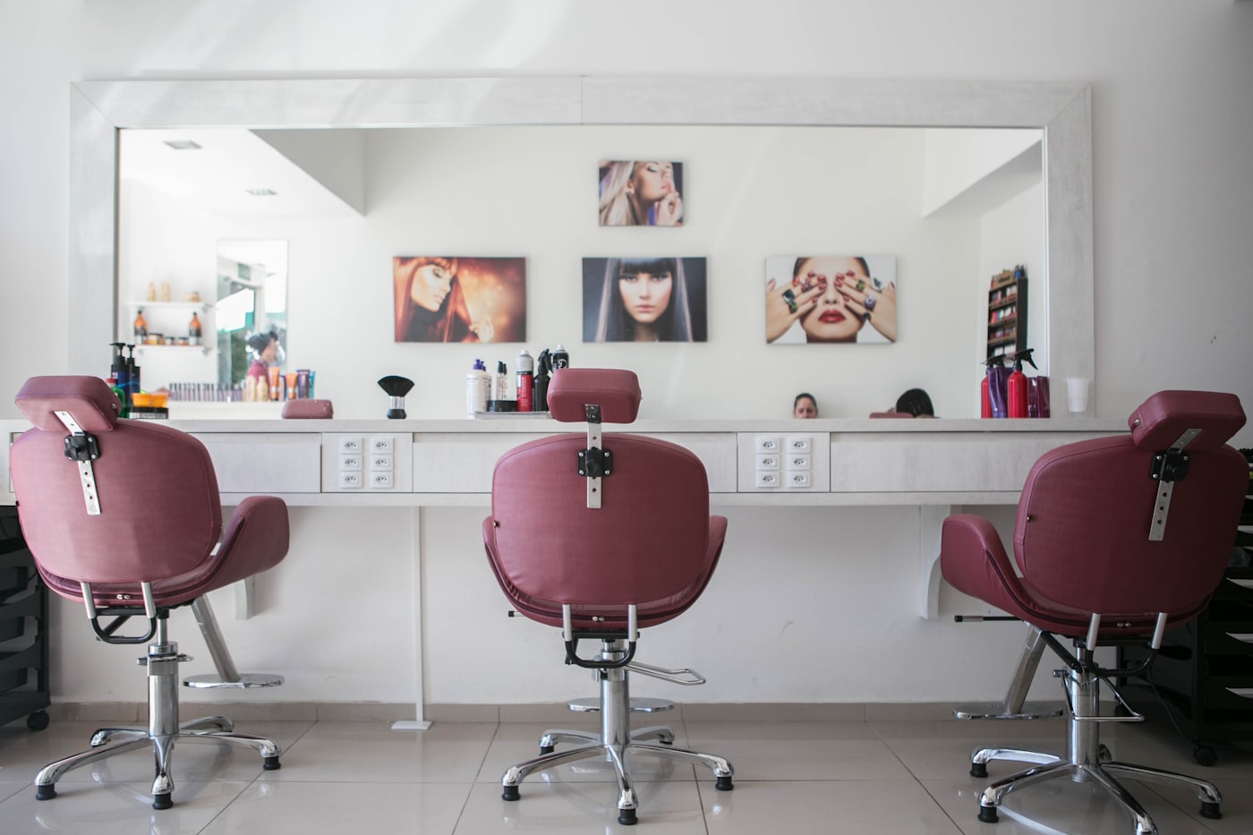 Trois fauteuils de coiffure face à un grand miroir dans un salon
