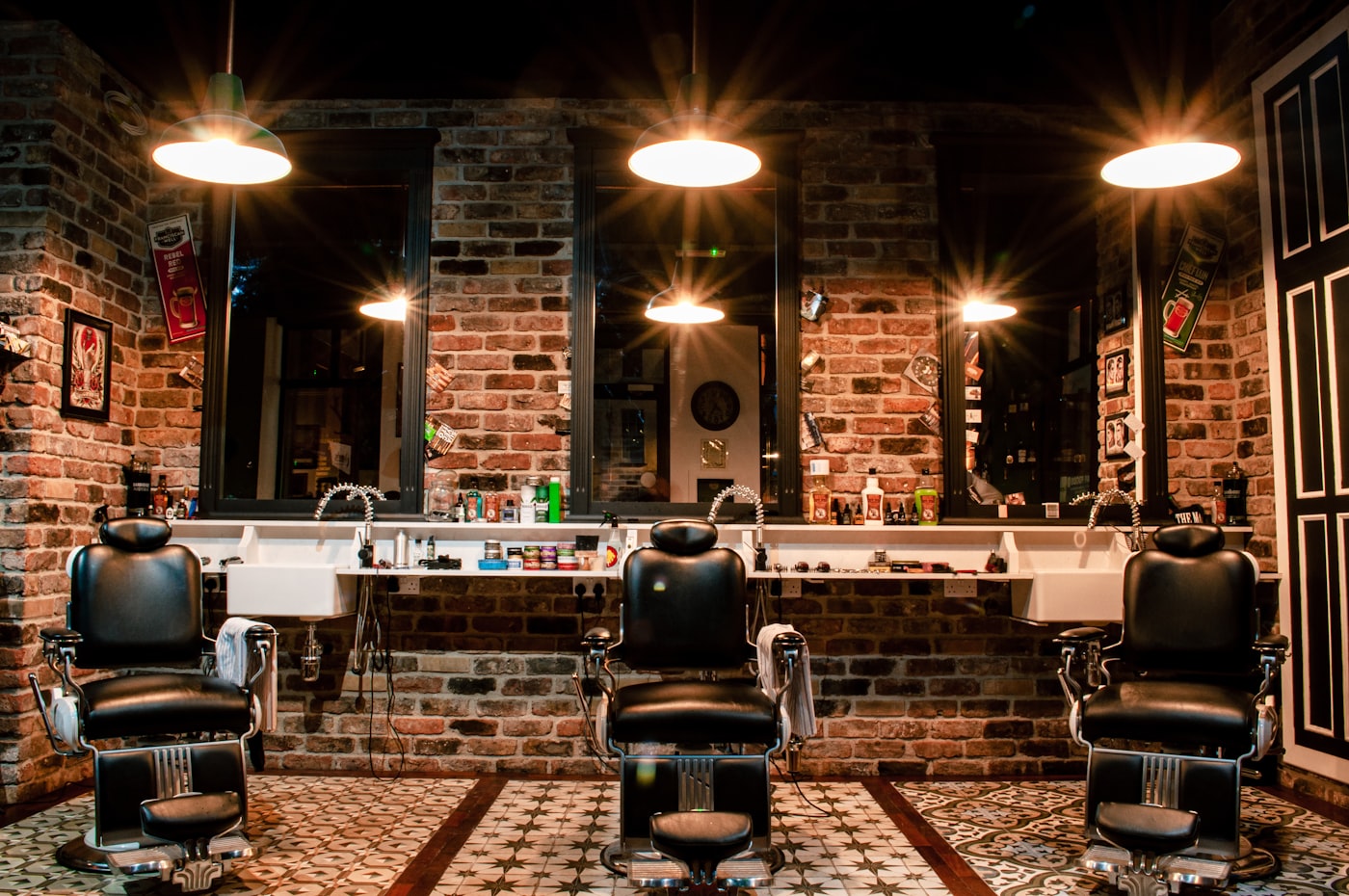 Trois fauteuils de barbier dans un barbershop aux murs de briques